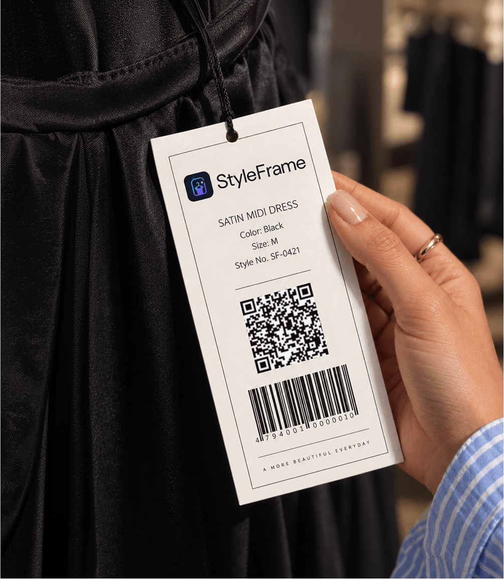 A StyleFrame garment hangtag with its QR code and barcode, held in front of a black dress